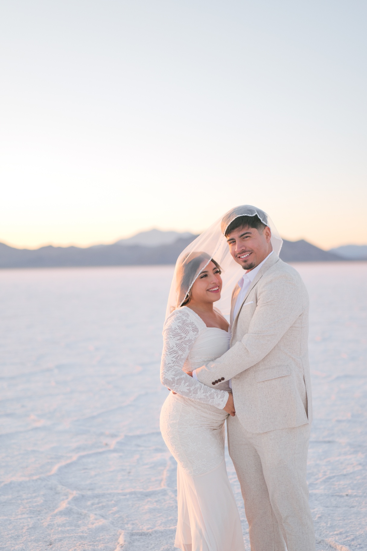 Bride and groom under a veil on the salt flats
