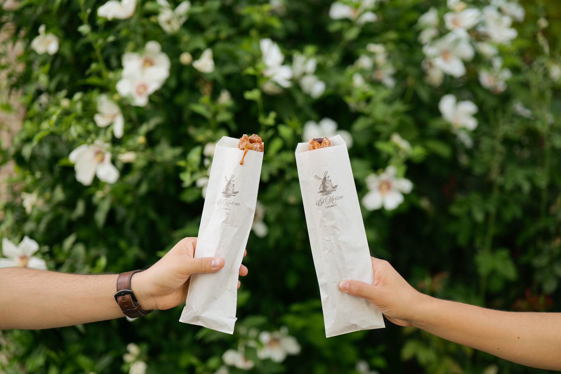 Churros held against white blooms