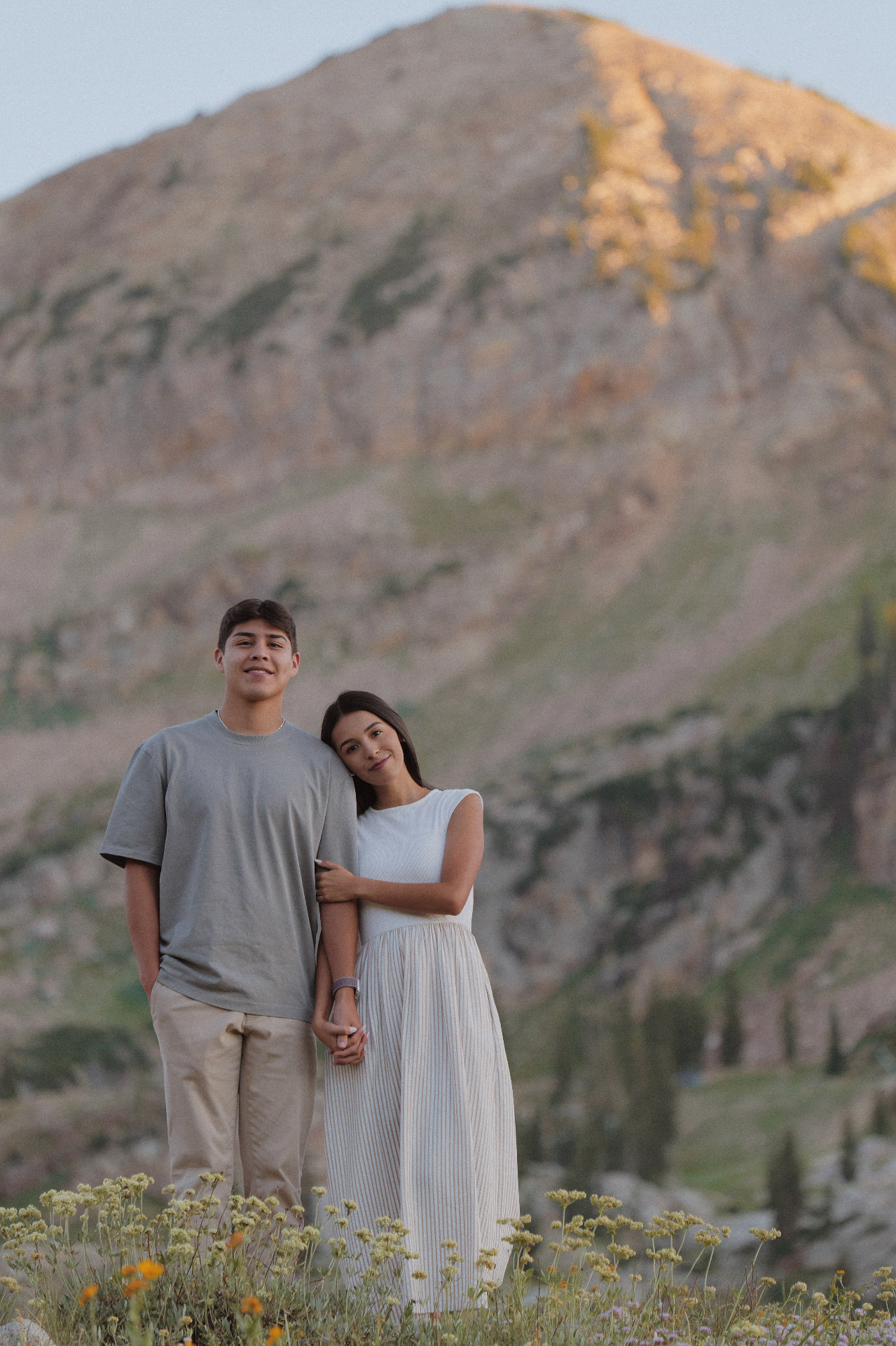 Young couple holding hands in a mountain meadow at golden hour