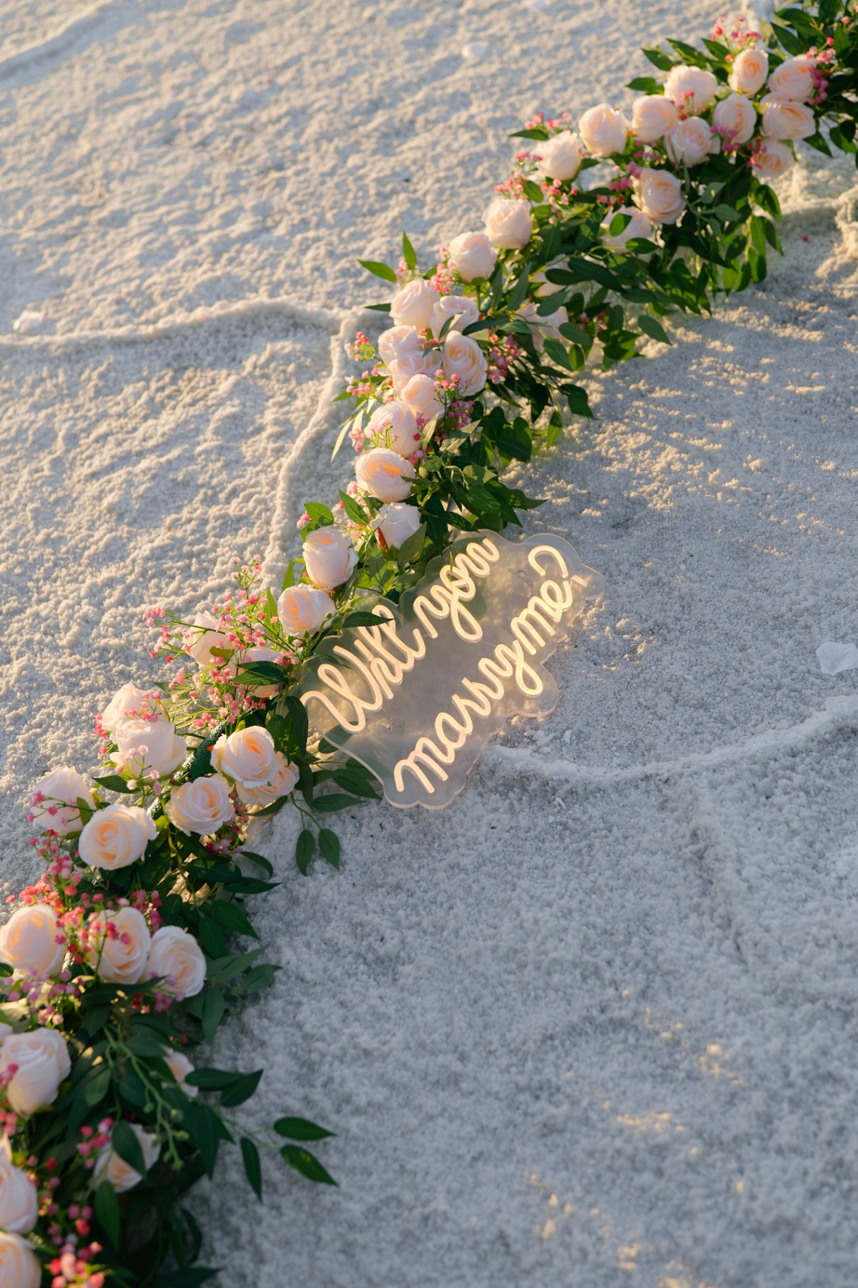 Will-you-marry-me neon sign nestled in roses