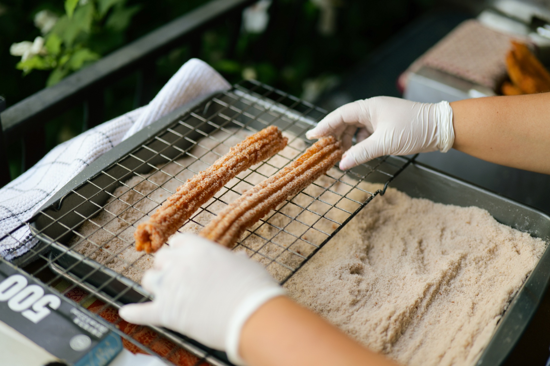 Fresh churros being dusted in cinnamon sugar