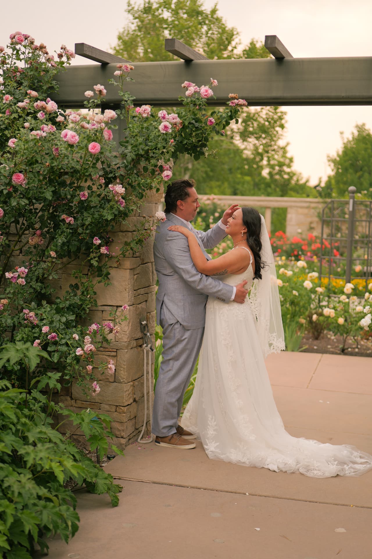 Bride and groom embracing under a rose arbor