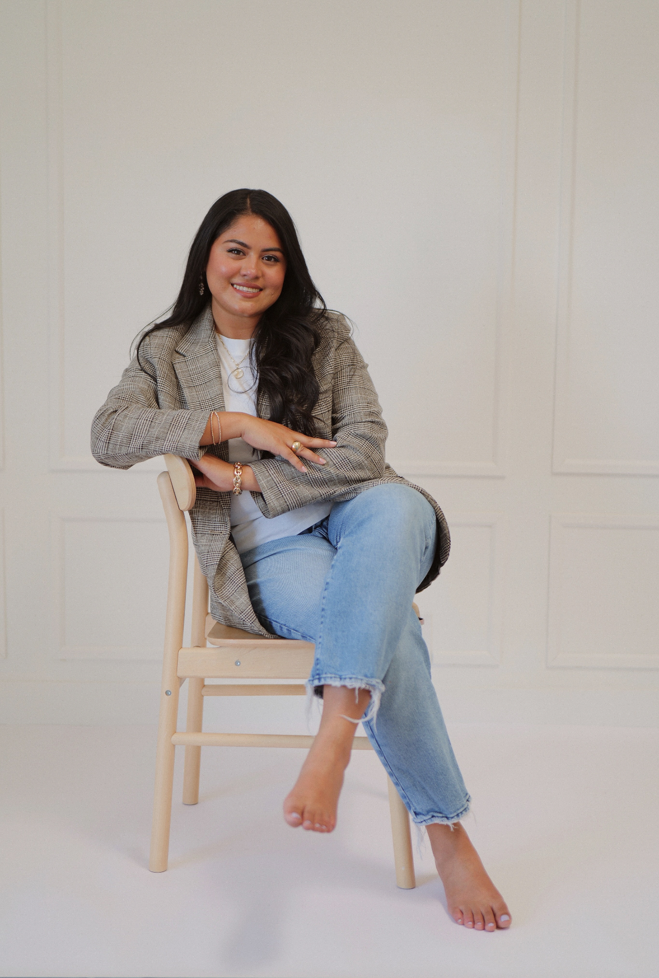 Branding portrait of a woman in a plaid blazer seated on a wooden chair