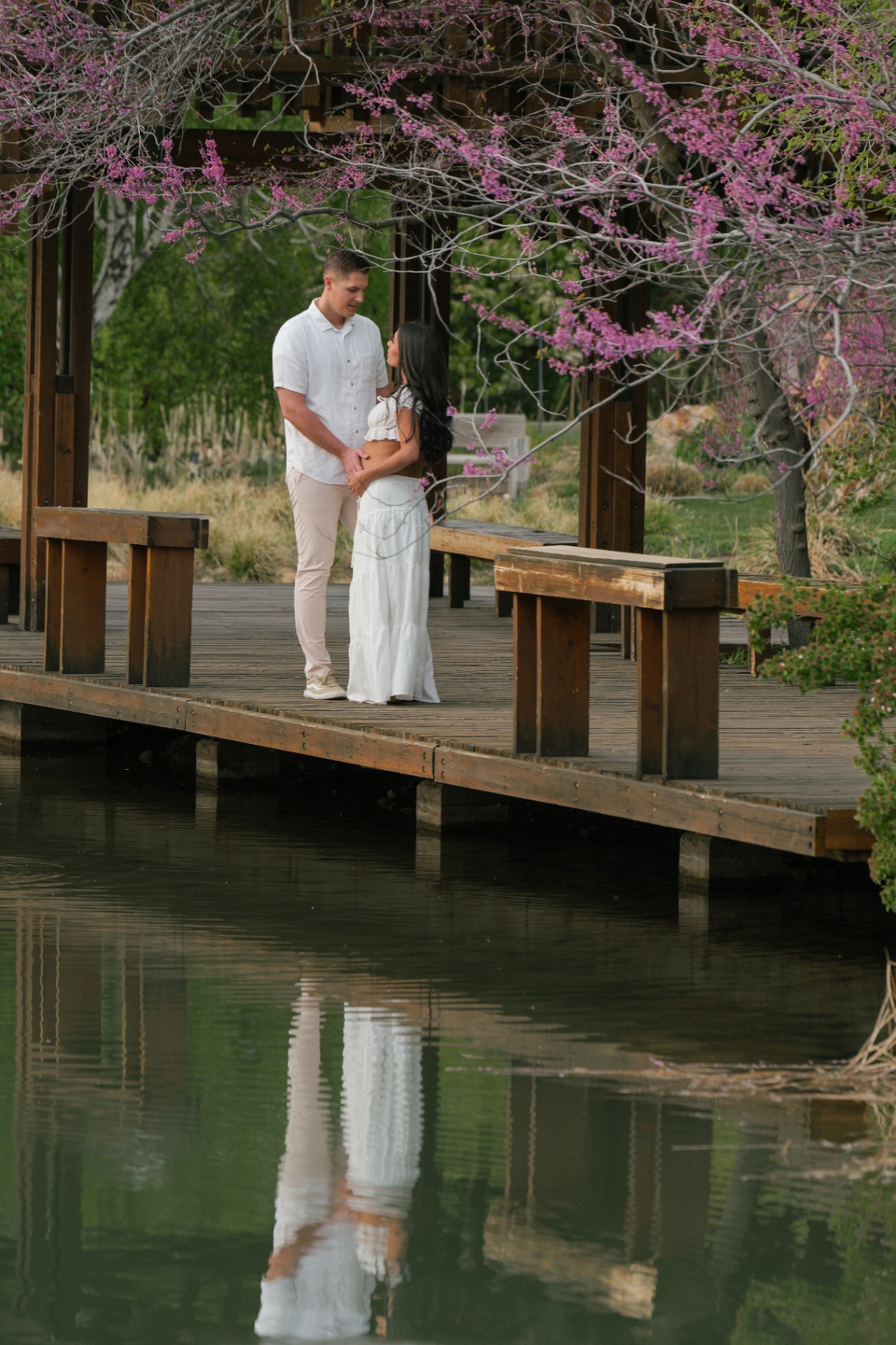 Couple on a wooden dock beneath cherry blossoms